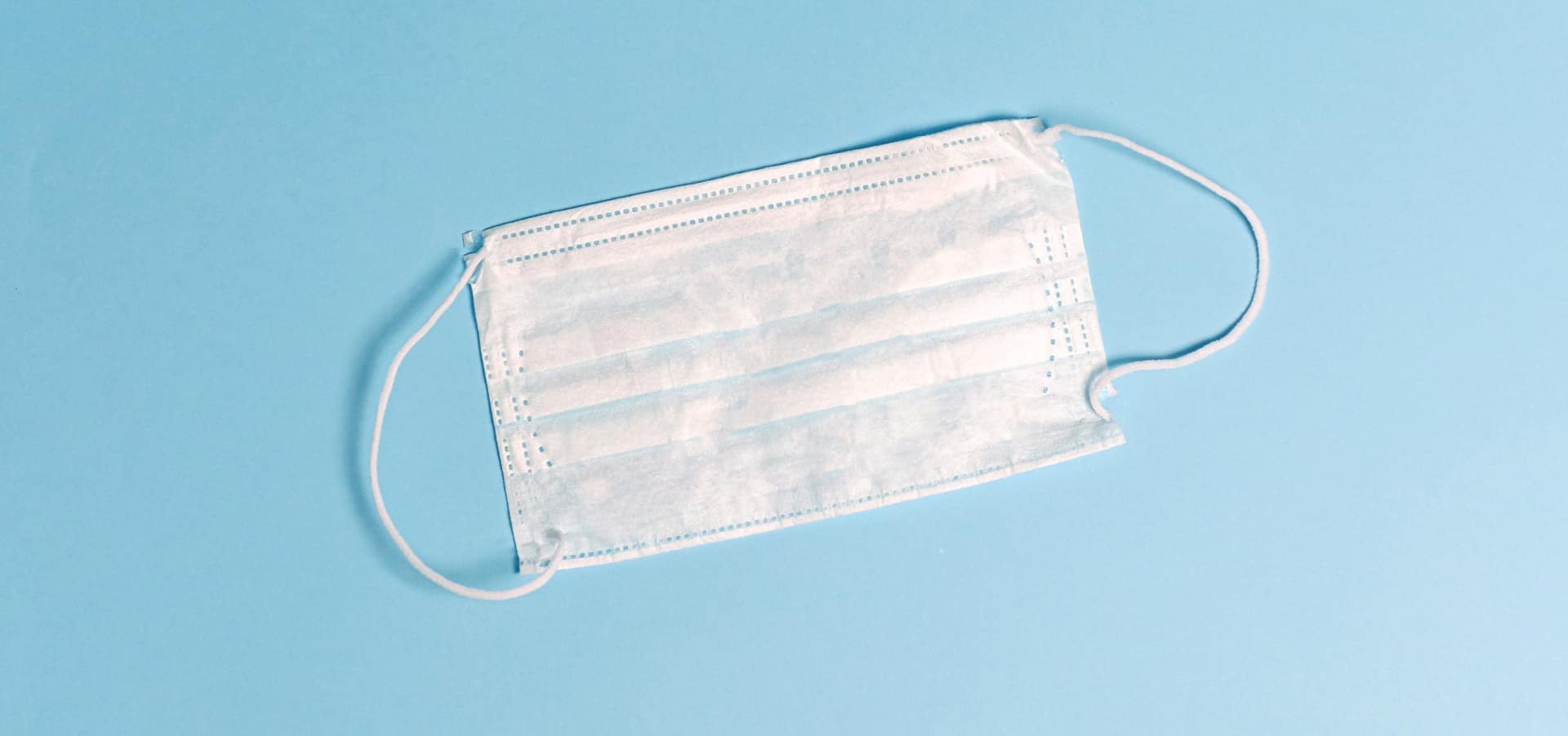 white disposable face mask on light blue background