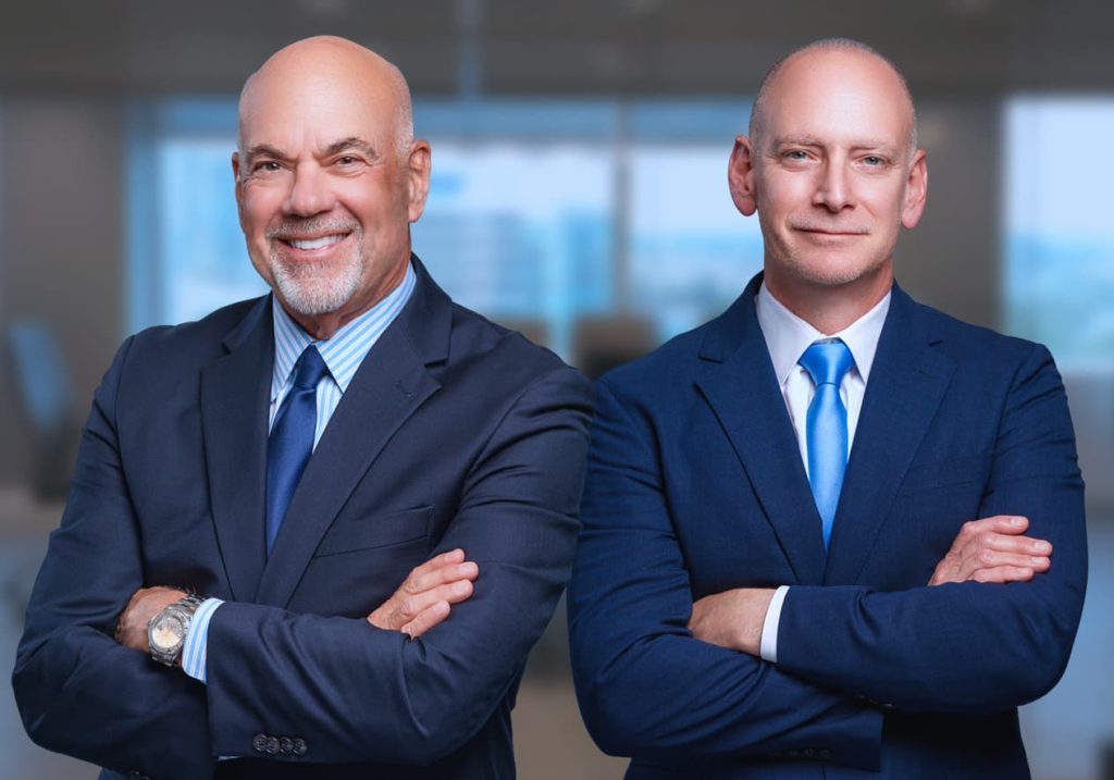 Jay Cohen and Jeff Blostein, Partners and Florida Attorneys Jay Cohen and Jeff Blostein office portrait, in front of blurred conference room